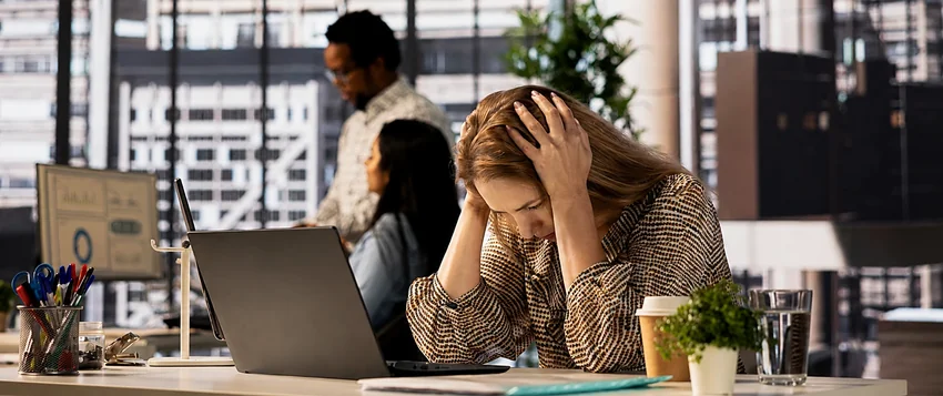 Professional experiencing workplace stress and burnout while working at a laptop