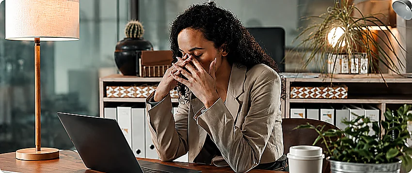 Professional woman experiencing workplace burnout at her office desk